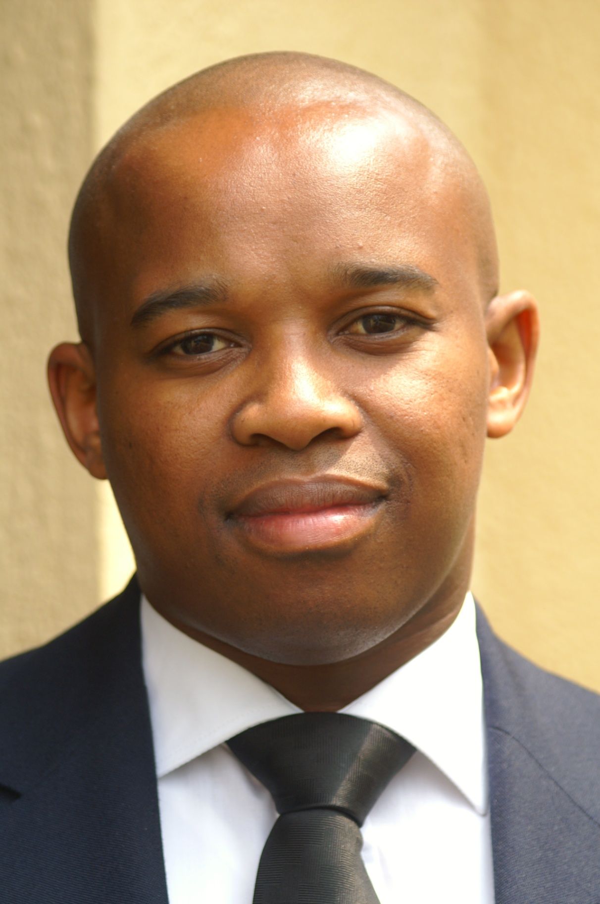 Siya Mapoko smiling in a navy suit